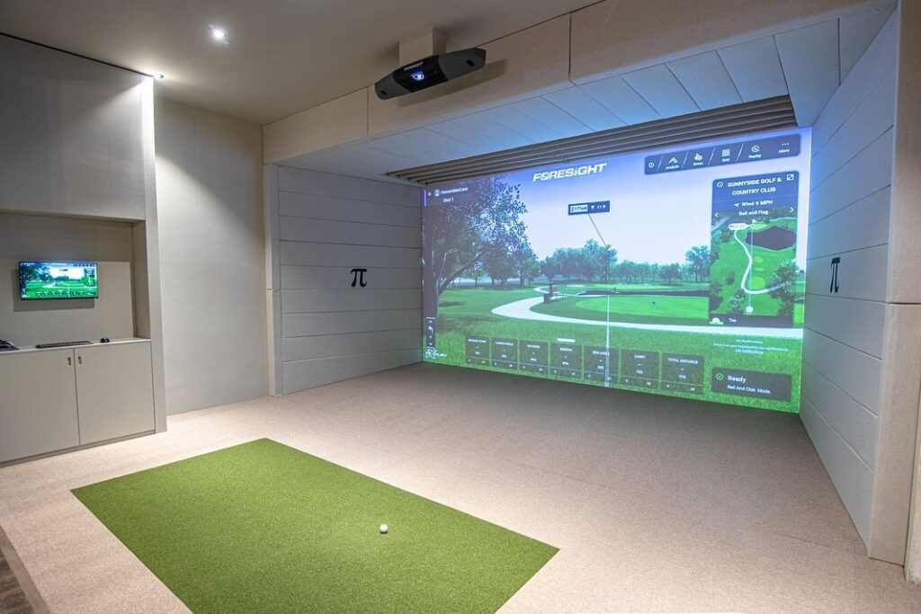 Foresight Falcon SIG12 golf simulator installed in a dedicated room with overhead launch monitor, impact screen, and turf hitting mat
